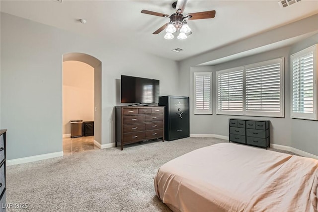 bedroom featuring arched walkways, multiple windows, light carpet, and baseboards