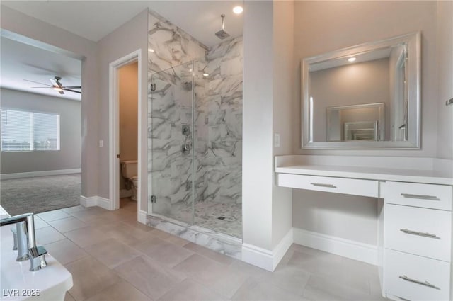 bathroom with baseboards, toilet, vanity, and a marble finish shower