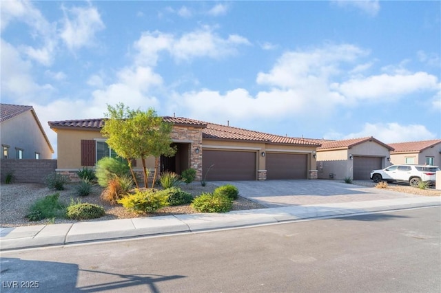 mediterranean / spanish house featuring stone siding, fence, decorative driveway, and stucco siding