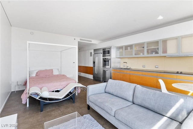 bedroom with visible vents, high quality fridge, baseboards, and a sink