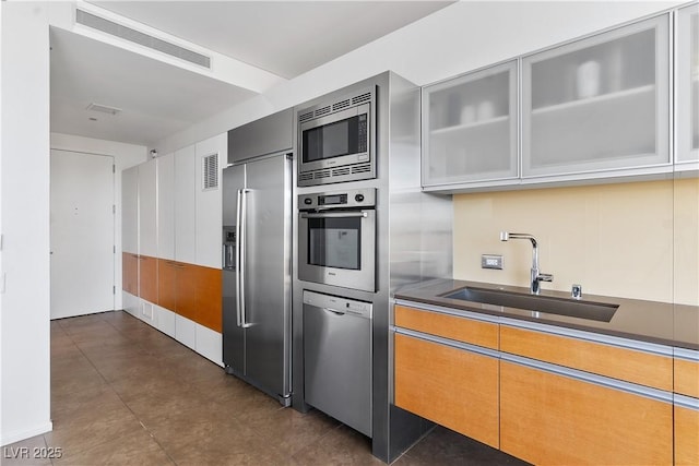 kitchen featuring visible vents, stainless steel appliances, glass insert cabinets, and a sink