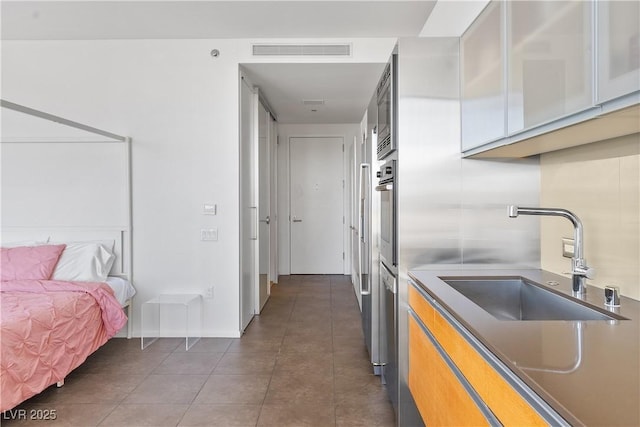 kitchen with tile patterned flooring, visible vents, glass insert cabinets, stainless steel oven, and a sink