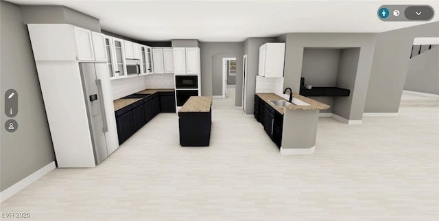 kitchen with baseboards, white cabinets, a sink, and oven