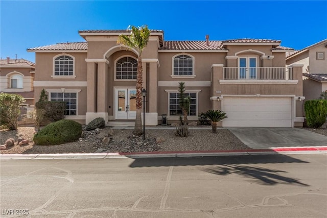 mediterranean / spanish house with driveway, french doors, a balcony, and stucco siding