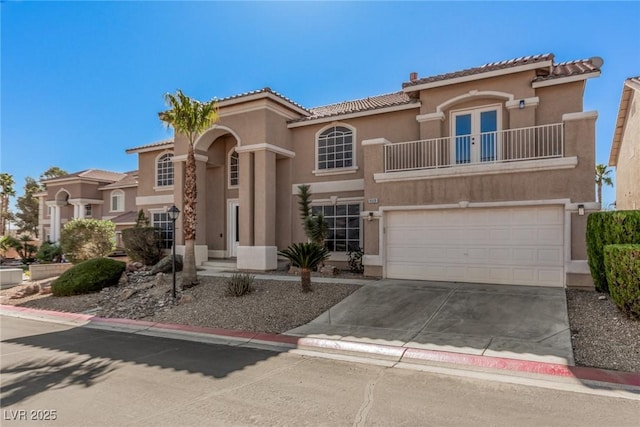 mediterranean / spanish-style house with a balcony, driveway, and stucco siding