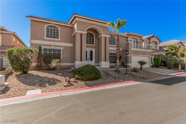 mediterranean / spanish-style house with a balcony, a garage, concrete driveway, french doors, and stucco siding