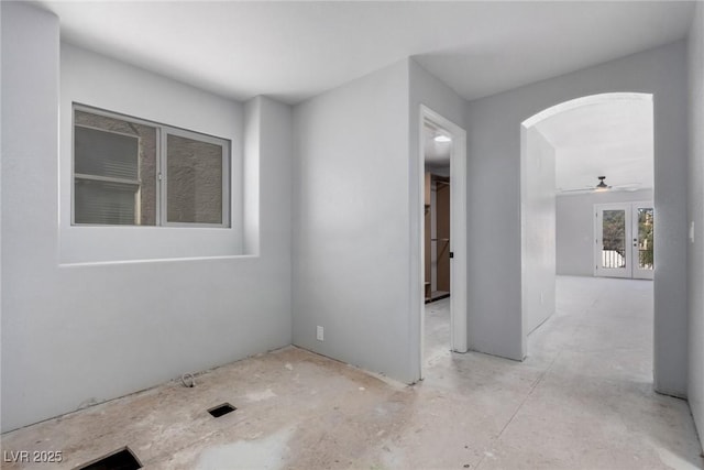 unfurnished room with arched walkways and french doors