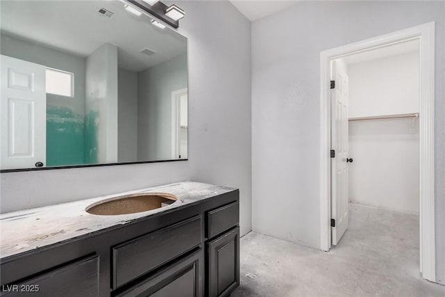 bathroom featuring visible vents, concrete floors, a walk in closet, and vanity