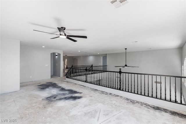 spare room featuring arched walkways, ceiling fan, visible vents, and concrete flooring