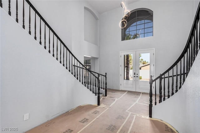 foyer featuring a towering ceiling, stairs, and french doors