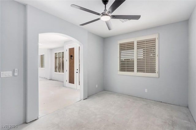 spare room with concrete flooring, arched walkways, and ceiling fan