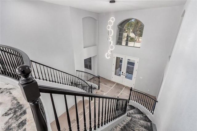 stairs featuring french doors and a towering ceiling