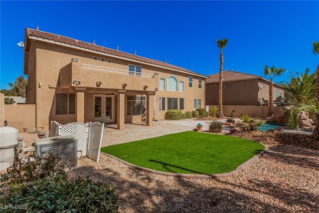 rear view of house with french doors, a patio, stucco siding, a lawn, and fence