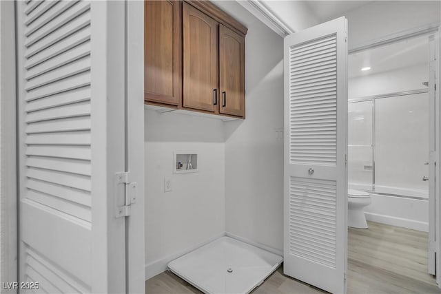 laundry room featuring hookup for a washing machine, cabinet space, and light wood-style floors