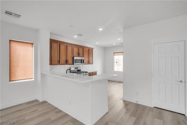 kitchen featuring light wood-style flooring, visible vents, light countertops, appliances with stainless steel finishes, and brown cabinetry