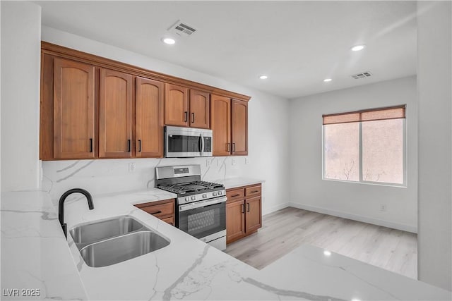 kitchen featuring light stone counters, appliances with stainless steel finishes, a sink, and visible vents