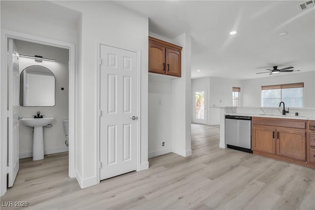 kitchen featuring a sink, visible vents, light countertops, light wood-type flooring, and dishwasher