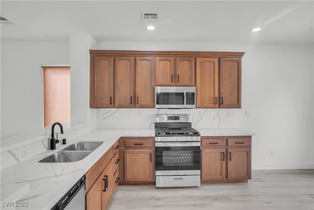 kitchen featuring visible vents, appliances with stainless steel finishes, light stone counters, and a sink