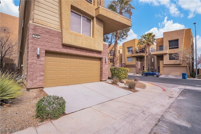 view of front of home featuring a garage, concrete driveway, and a balcony