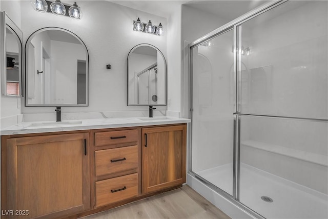 full bathroom with a sink, a shower stall, and double vanity