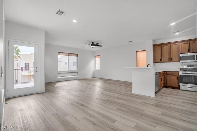 kitchen with stainless steel appliances, a peninsula, visible vents, open floor plan, and light countertops