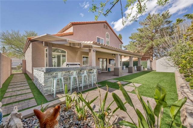 back of property with a tile roof, outdoor dry bar, stucco siding, a patio area, and fence