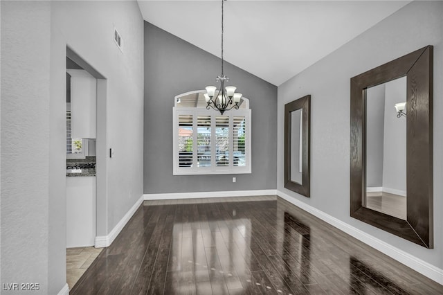 unfurnished dining area featuring a notable chandelier, visible vents, wood finished floors, high vaulted ceiling, and baseboards