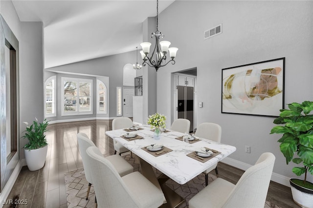 dining space with baseboards, visible vents, dark wood-style floors, high vaulted ceiling, and a chandelier