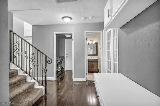 foyer entrance featuring a textured ceiling, washing machine and dryer, dark wood-style flooring, visible vents, and baseboards