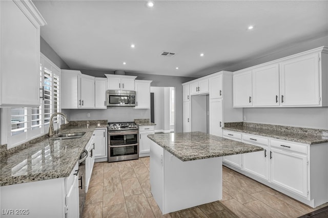 kitchen featuring stainless steel appliances, visible vents, white cabinetry, a sink, and light stone countertops