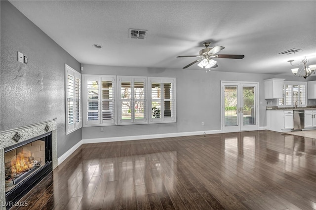 unfurnished living room featuring visible vents, a fireplace, baseboards, and hardwood / wood-style flooring