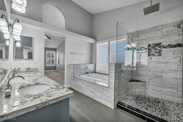 bathroom with a garden tub, double vanity, a stall shower, and a sink