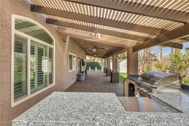 view of patio featuring an outdoor kitchen, fence, a ceiling fan, grilling area, and a pergola