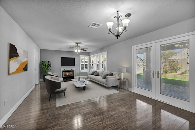 living area with visible vents, wood finished floors, a lit fireplace, a textured ceiling, and french doors