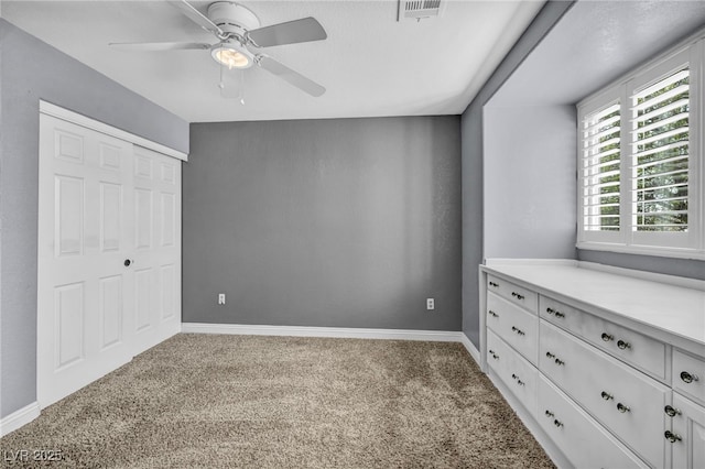 unfurnished bedroom featuring carpet floors, a closet, visible vents, a ceiling fan, and baseboards