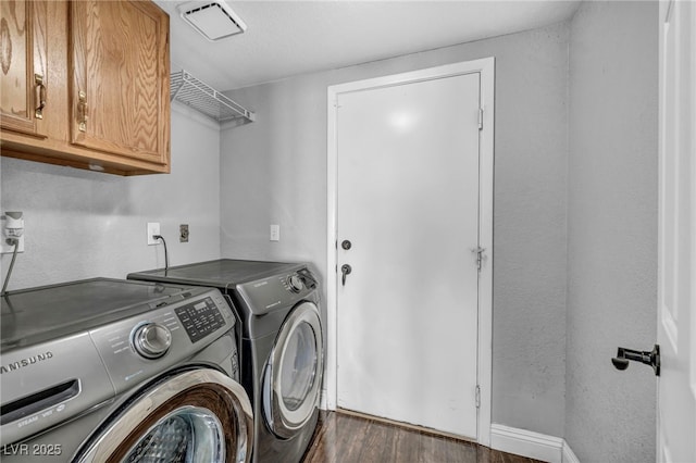 laundry room featuring visible vents, dark wood finished floors, washing machine and clothes dryer, and cabinet space