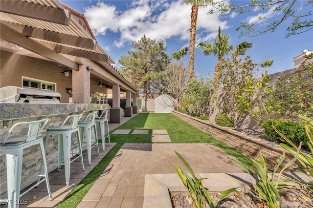 view of patio / terrace with an outbuilding, a storage shed, exterior bar, and a ceiling fan