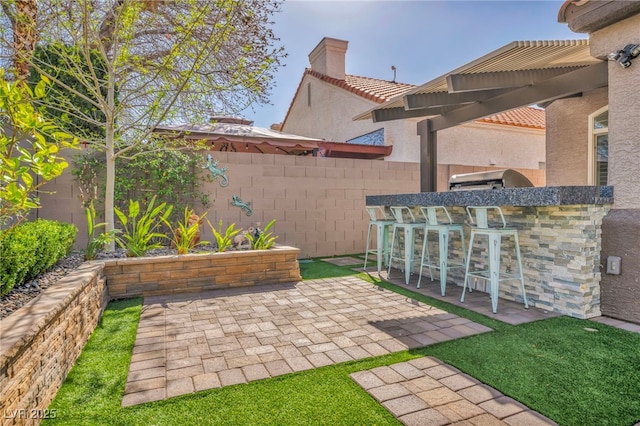 view of patio featuring outdoor dry bar, area for grilling, and fence