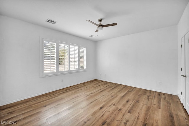 empty room featuring ceiling fan, visible vents, baseboards, and wood finished floors