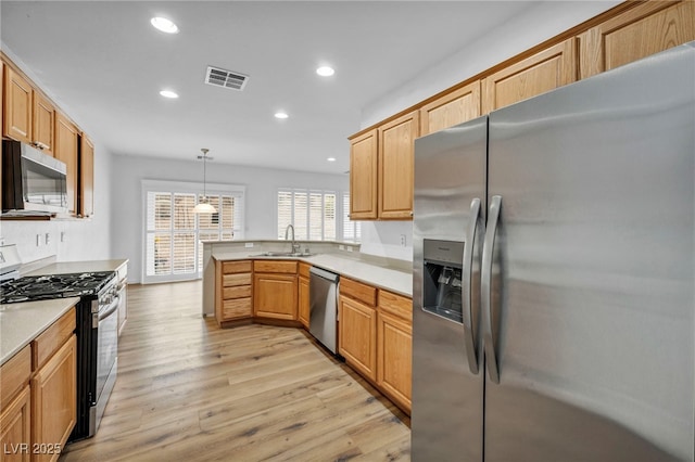 kitchen featuring visible vents, light wood-type flooring, a sink, appliances with stainless steel finishes, and a peninsula