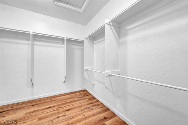 spacious closet with attic access and wood finished floors