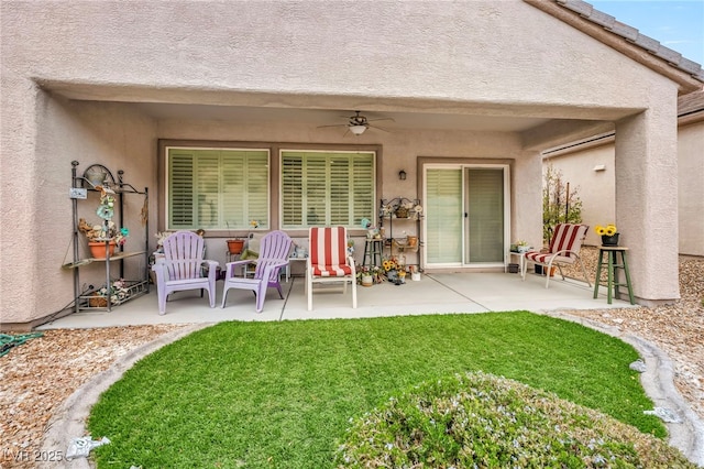 exterior space with a patio area, stucco siding, a yard, and ceiling fan