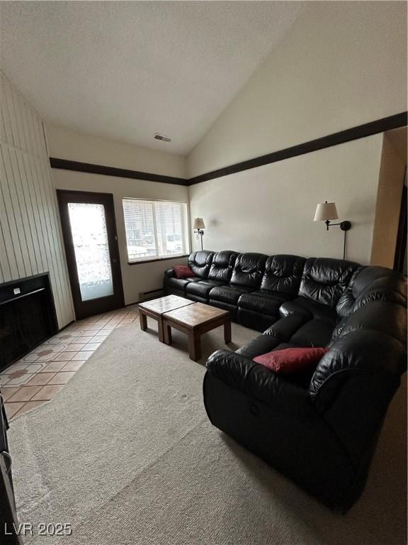 living room featuring light tile patterned floors, visible vents, light colored carpet, lofted ceiling, and a textured ceiling