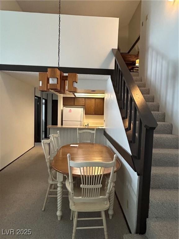 carpeted dining space with stairs