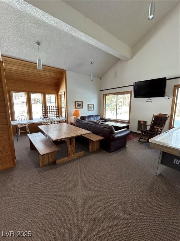 carpeted living room featuring plenty of natural light, beam ceiling, high vaulted ceiling, and a textured ceiling