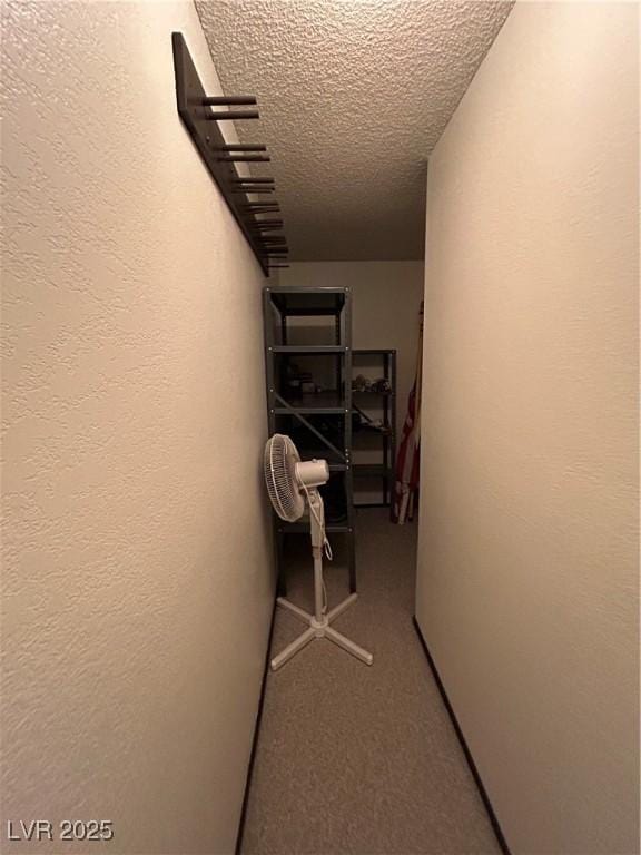 hallway featuring a textured ceiling and a textured wall