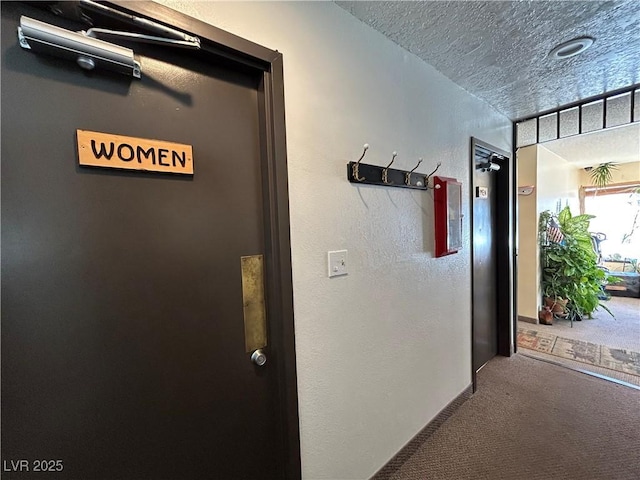 hall featuring elevator, carpet flooring, a textured wall, and a textured ceiling