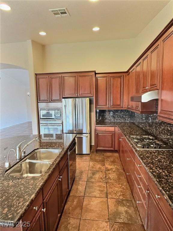 kitchen featuring tasteful backsplash, visible vents, appliances with stainless steel finishes, under cabinet range hood, and a sink