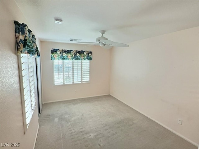 carpeted empty room with baseboards, visible vents, and a ceiling fan