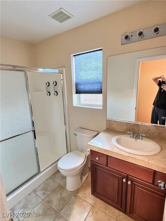 bathroom featuring toilet, vanity, visible vents, tile patterned floors, and a stall shower